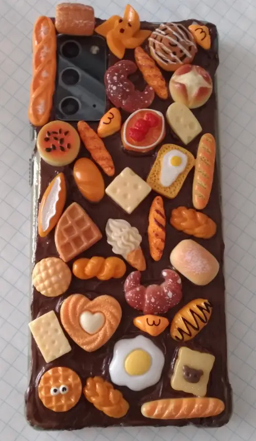 The finished project - bread charms embedded on what looks like chocolate covering a clear cell phone case.